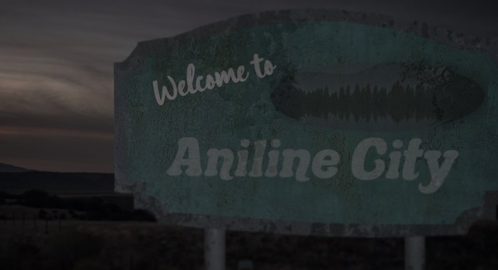 The Aniline City sign - slightly rusted and worn with the words Welcome to Aniline City